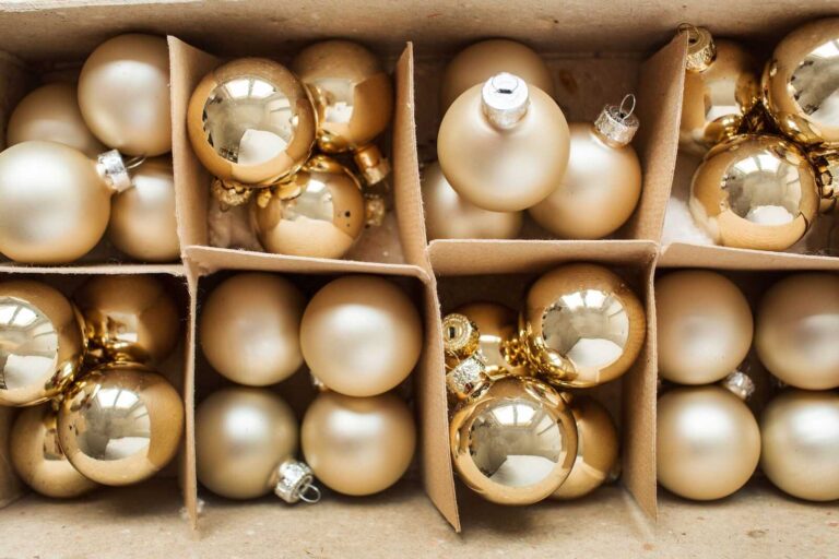 Gold and champagne Christmas ornaments neatly stored in a divided holiday storage box.
