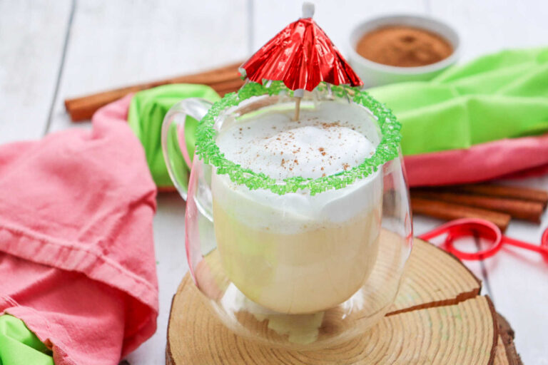 Eggnog milkshake with whipped cream, nutmeg, and green sugar rim in glass mug