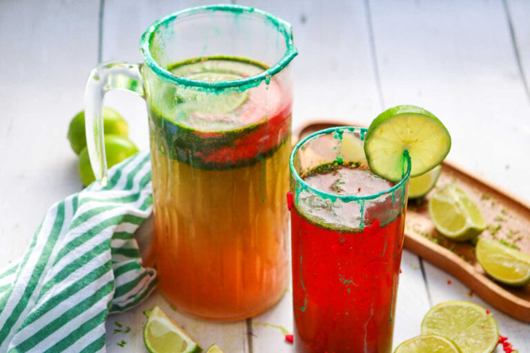 Grinch Mocktail pitcher and glass with lime garnish and festive red and green drink.