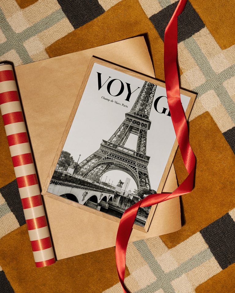 Framed black and white Eiffel Tower “VOYAGE” art print on kraft paper with red ribbon and striped wrapping paper.