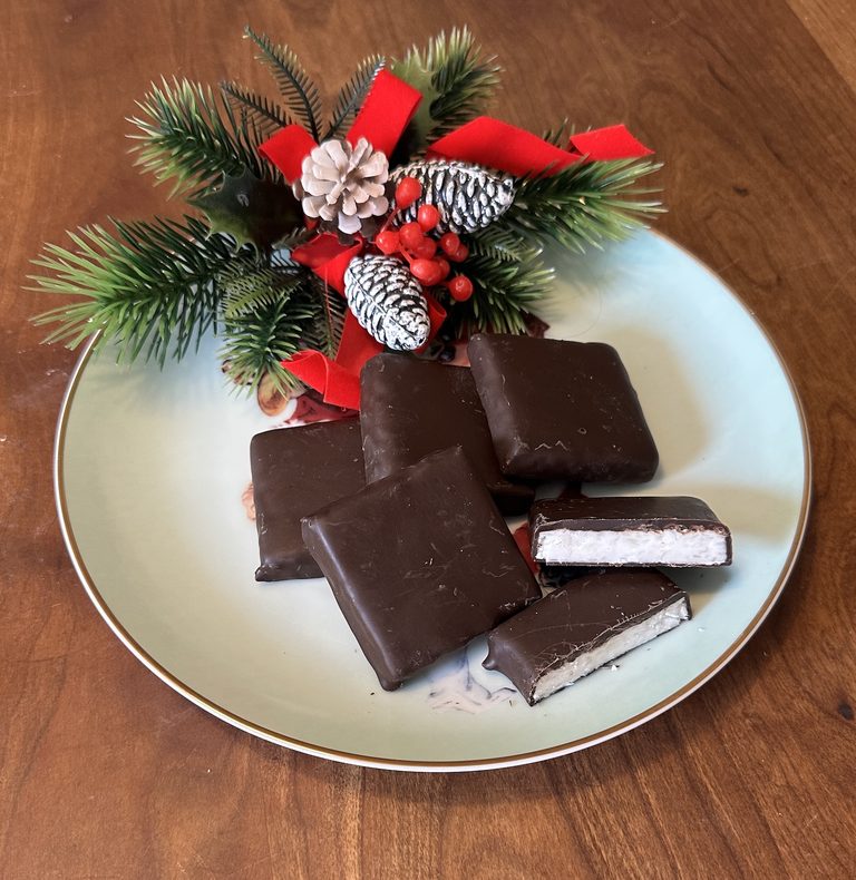 Needhams Christmas recipe with chocolate-covered coconut candy squares on a plate.