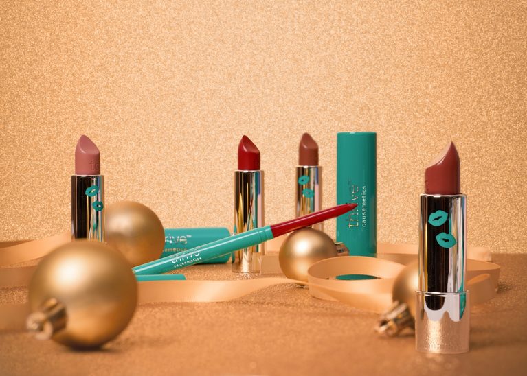 Thrive Causemetics Holiday Beauty Bundles lipsticks and lip liner on gold glitter.